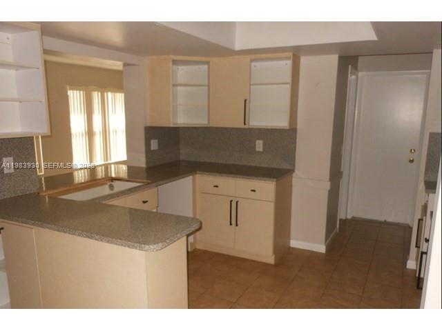 A kitchen features light wood cabinets, granite countertops, and tile flooring — 7540 Margate Blvd, Margate FL 33063, MARGATE, FL