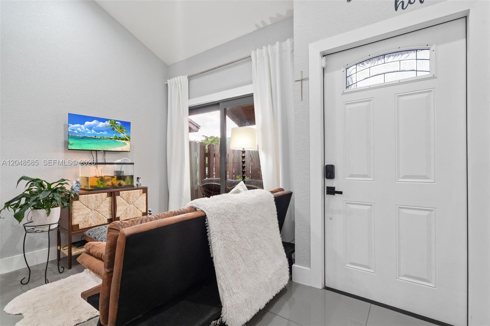 A living room features a brown sofa, a television, a fish tank, and a door — 1946 SW 81st Ter, Davie FL 33324, DAVIE, FL