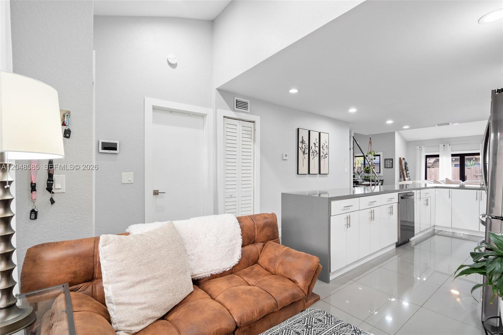 A living room with a brown leather sofa opens into a modern white kitchen — 1946 SW 81st Ter, Davie FL 33324, DAVIE, FL