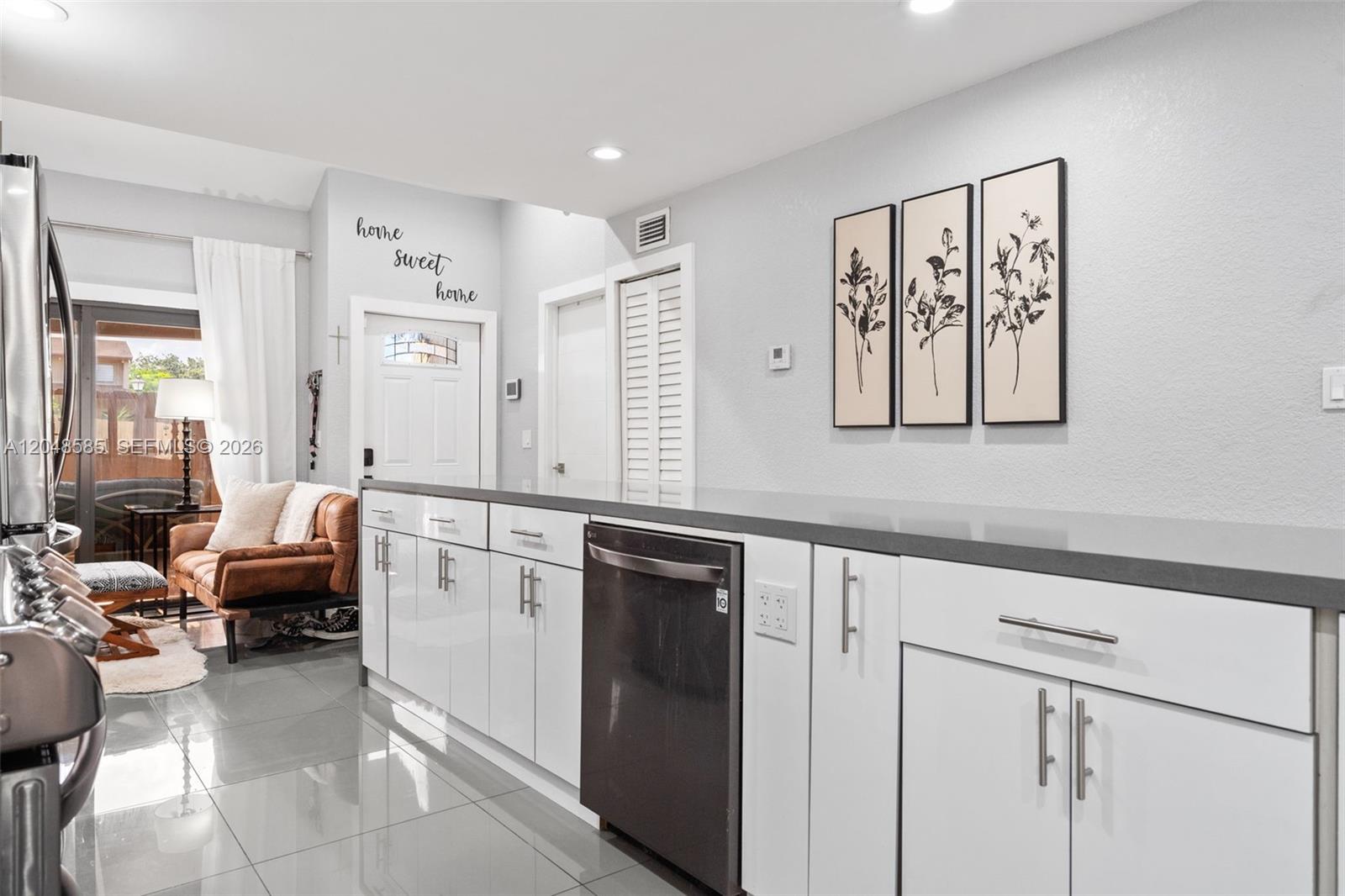 A modern kitchen features white cabinets, a dark countertop, and a dishwasher — 1946 SW 81st Ter, Davie FL 33324, DAVIE, FL