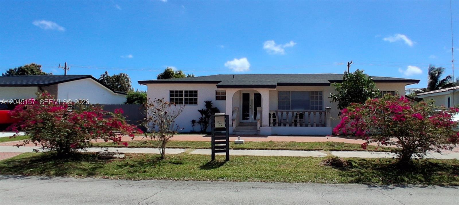 A single-story house with a white exterior, a dark roof, and blooming bougainvillea bushes — 8240 SW 38th St, Miami FL 33155, MIAMI, FL