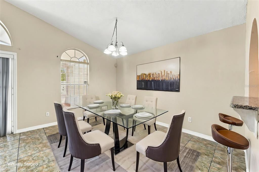 A dining room features a glass-topped table, six chairs, tile flooring, and a chandelier — 2411 PARSONS POND CIRCLE, KISSIMMEE, FL