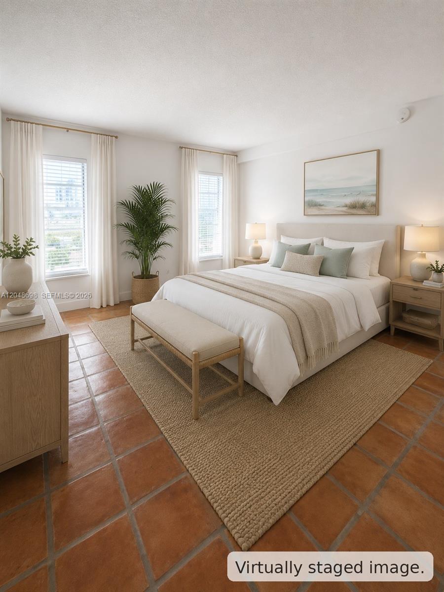This virtually staged bedroom features a bed, terracotta tile flooring, and two windows with curtains — 1345 West Ave # 702, Miami Beach FL 33139, MIAMI BEACH, FL