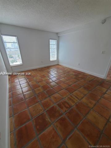An empty room with terracotta tile flooring and two windows overlooking a city view — 1345 West Ave # 702, Miami Beach FL 33139, MIAMI BEACH, FL