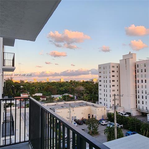 A view from a balcony overlooking a parking lot, surrounding buildings, and a sunset sky — 1345 West Ave # 702, Miami Beach FL 33139, MIAMI BEACH, FL