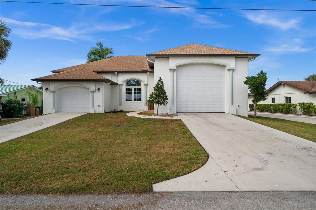 A single-story house with a white stucco exterior, two garage doors, and a brown roof — 2129 W TOBAGO CIRCLE, FORT MYERS, FL