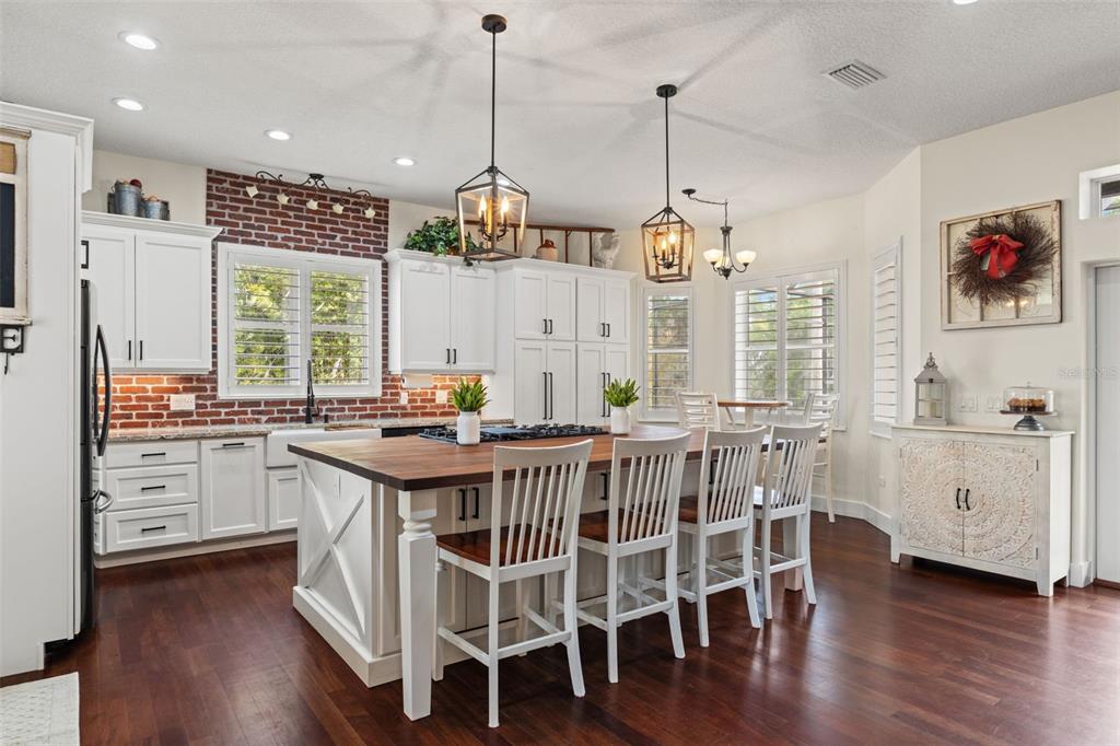 A kitchen with white cabinets, a brick backsplash, a large island, and stainless steel appliances — 18420 HANCOCK BLUFF ROAD, DADE CITY, FL