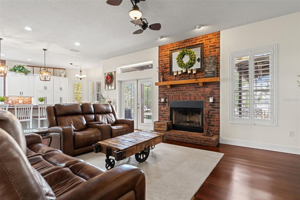 A kitchen features white cabinets, a wood-topped island with seating, and a brick backsplash — 18420 HANCOCK BLUFF ROAD, DADE CITY, FL