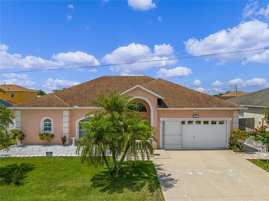 A single-story peach-colored house with a brown shingled roof and a two-car garage — 323 ALEGRIANO COURT, KISSIMMEE, FL
