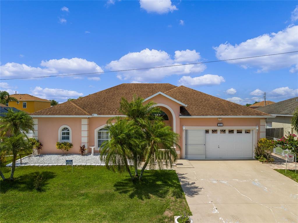 A single-story peach-colored house with a brown shingled roof, palm trees, and a driveway — 323 ALEGRIANO COURT, KISSIMMEE, FL
