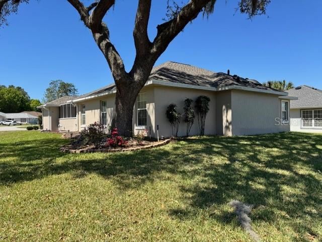 A large tree stands in the front yard of a single-story beige stucco house — 11299 SW 71ST TERRACE ROAD, OCALA, FL