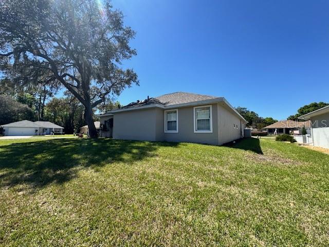 A side view of a beige house with a large tree on a grassy lot — 11299 SW 71ST TERRACE ROAD, OCALA, FL