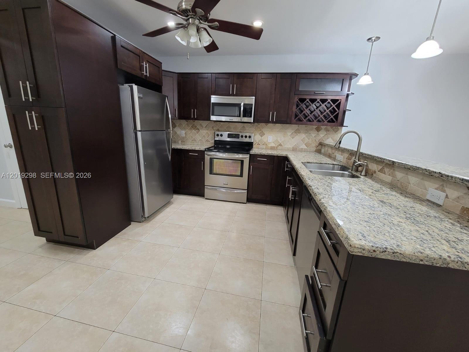 A kitchen features dark wood cabinets, granite countertops, stainless steel appliances, and tile flooring — 5780 SW 61st St # 5780, Miami FL 33143, MIAMI, FL