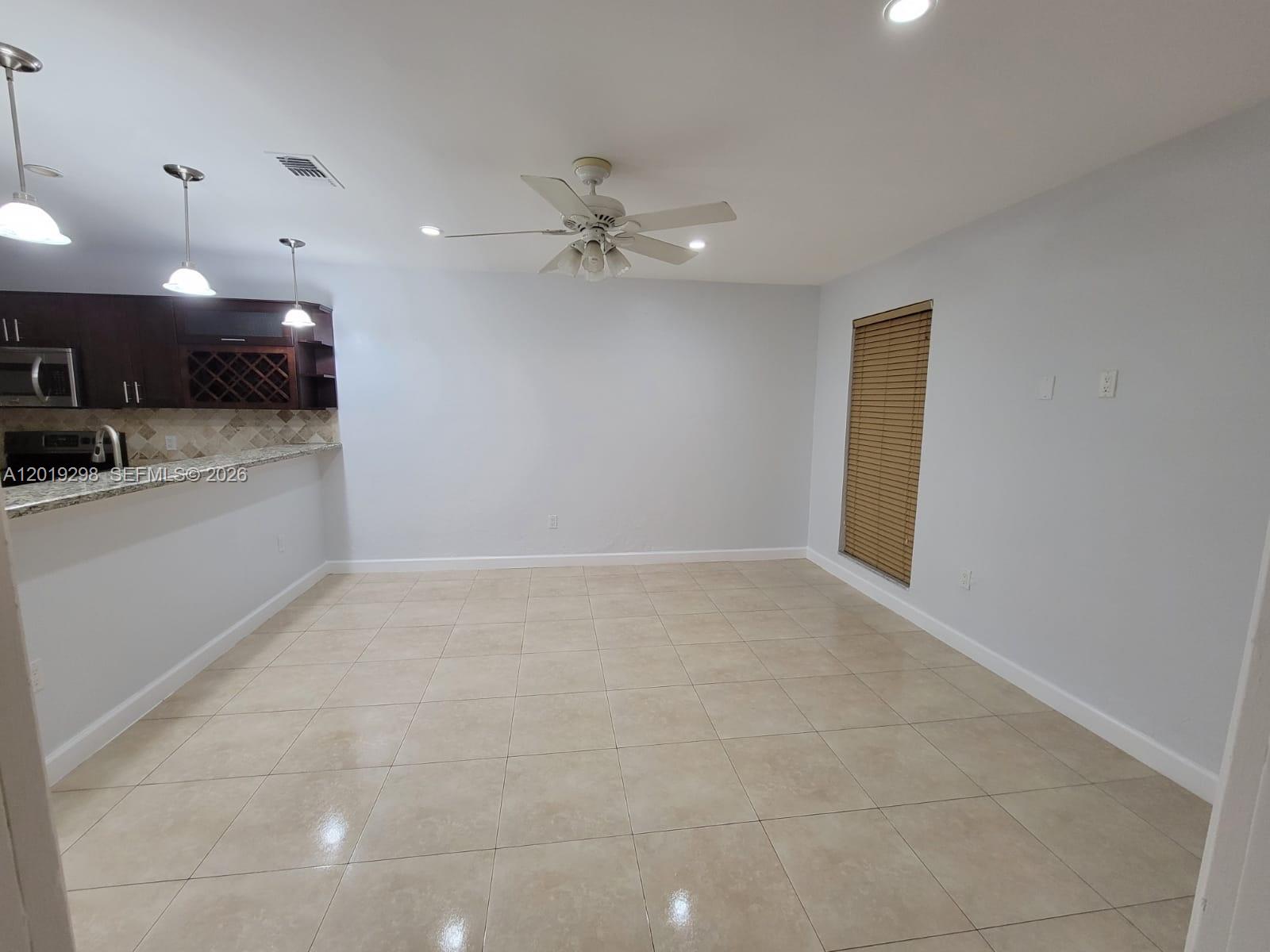 An empty dining area features light tile flooring, a ceiling fan, and an adjacent kitchen — 5780 SW 61st St # 5780, Miami FL 33143, MIAMI, FL
