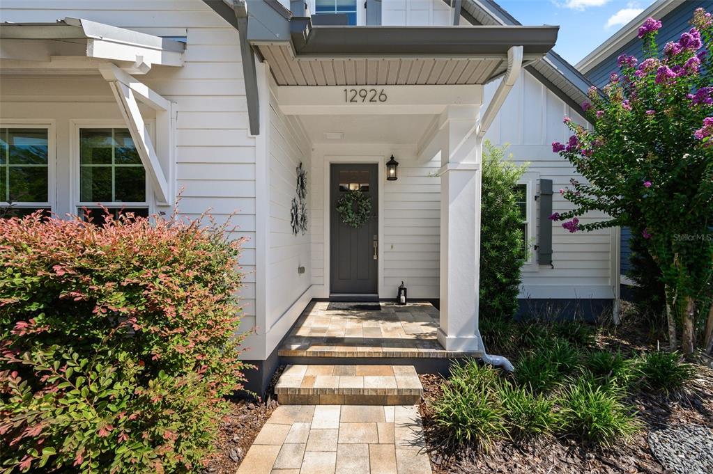 A front porch with a gray door, stone steps, and white siding on a house — 12926 SW 7TH AVENUE, NEWBERRY, FL