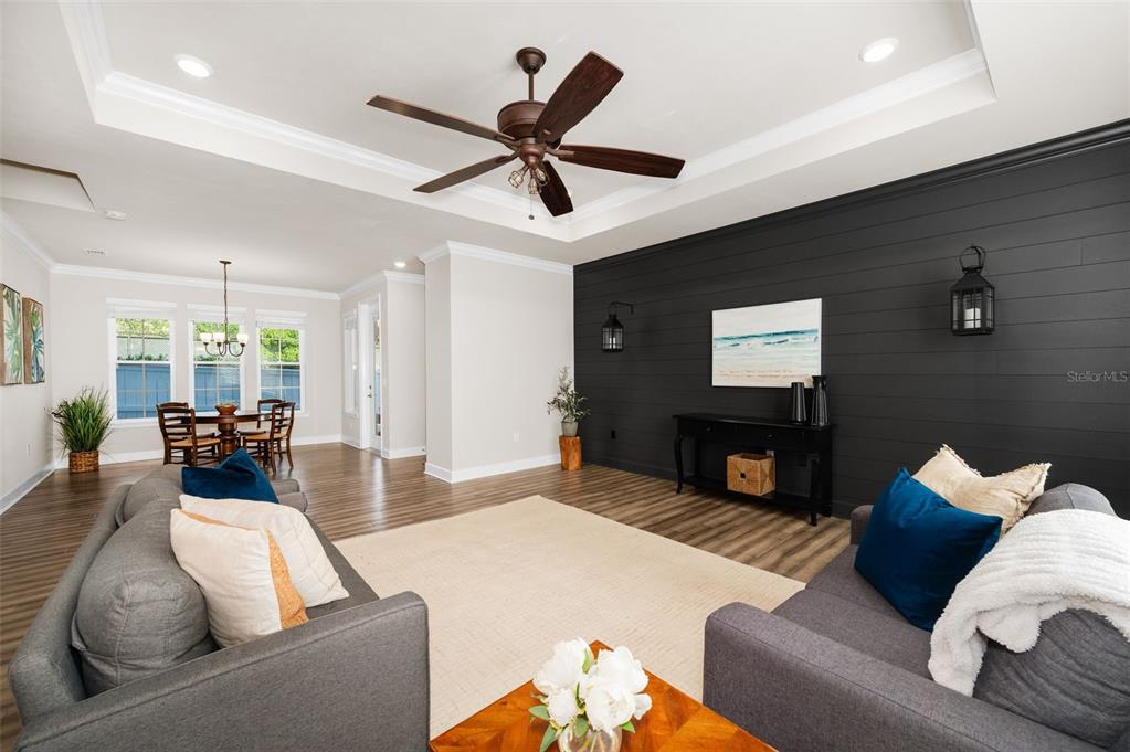 A living room features a dark shiplap accent wall, gray sofas, and a tray ceiling — 12926 SW 7TH AVENUE, NEWBERRY, FL