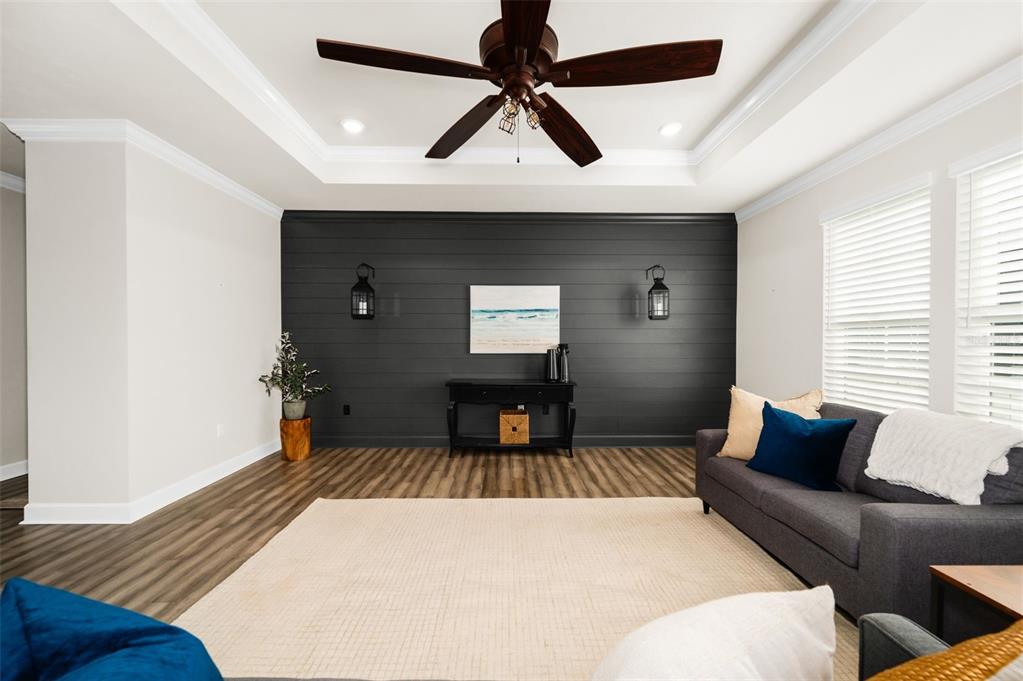 A living room features a dark shiplap accent wall, a tray ceiling, and wood flooring — 12926 SW 7TH AVENUE, NEWBERRY, FL