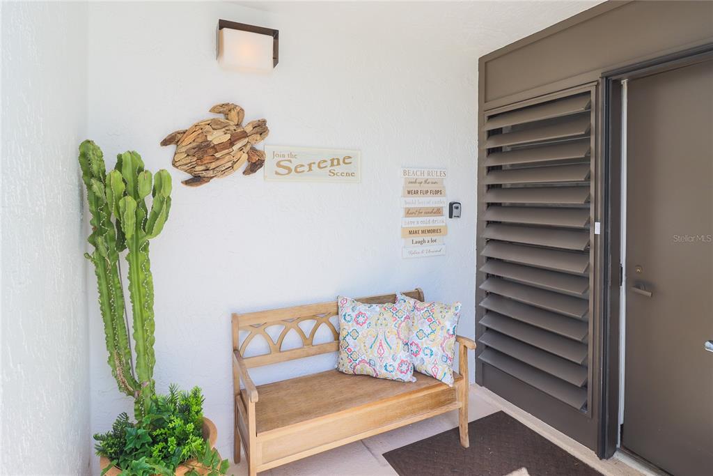 A wooden bench with patterned pillows sits on a patio next to a potted cactus — 716 BAYPORT WAY UNIT 716, LONGBOAT KEY, FL