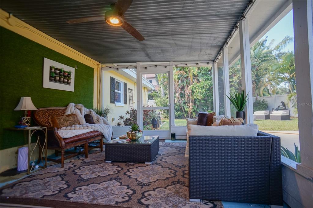 A screened-in porch features a green accent wall, wicker furniture, and a patterned area rug — 328 CARL AVENUE, BELLEAIR, FL