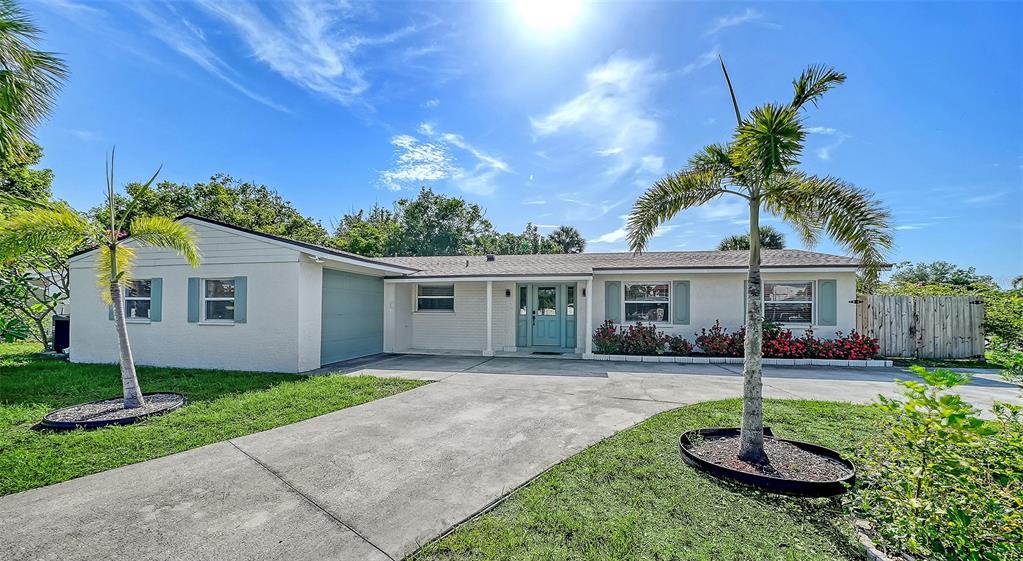 A single-story house with a light-colored exterior, a concrete driveway, and two palm trees — 6515 COLONIAL DRIVE, SARASOTA, FL