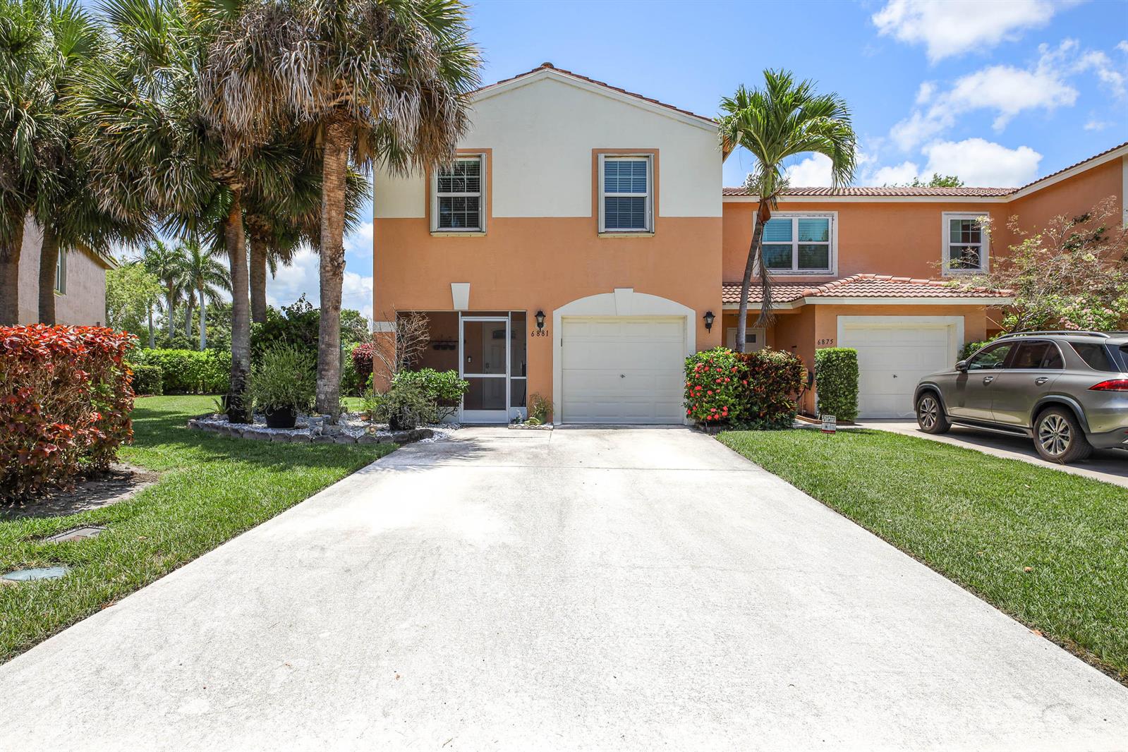 A two-story townhouse with a concrete driveway, a garage, and palm trees in the front — 6881 Willow Creek Run, FL 33463, FL