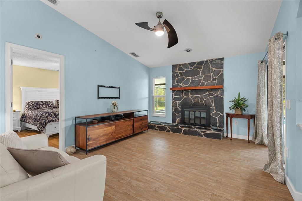 A living room features light blue walls, wood-look flooring, a stone fireplace, and a ceiling fan — 4204 PRAIRIE VIEW DRIVE, SARASOTA, FL