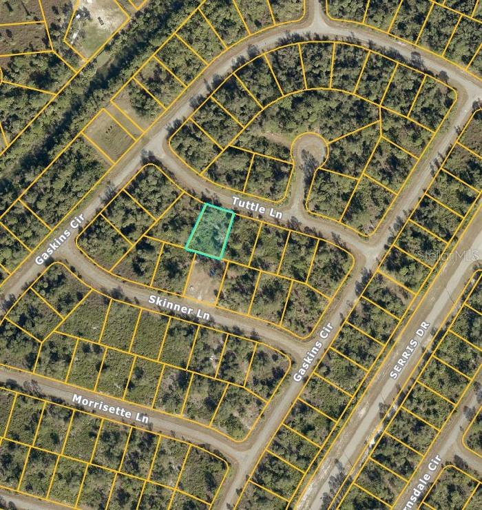 This is an aerial map showing a highlighted vacant residential lot in a wooded neighborhood — TUTTLE LANE, NORTH PORT, FL