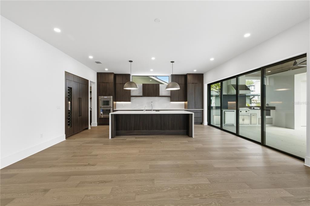 A modern kitchen features dark wood cabinetry, a large center island, and floor-to-ceiling glass doors — 2517 RIVERSIDE DR, TAMPA, FL