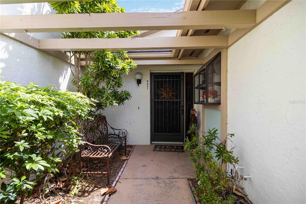 A paved walkway leads to a front door with a security gate and a bench — 6521 HERITAGE LANE UNIT 2621, BRADENTON, FL