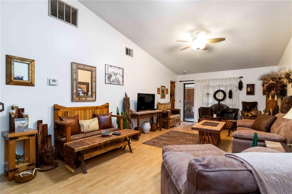 A living room features light wood flooring, rustic wooden furniture, and a vaulted ceiling — 6521 HERITAGE LANE UNIT 2621, BRADENTON, FL
