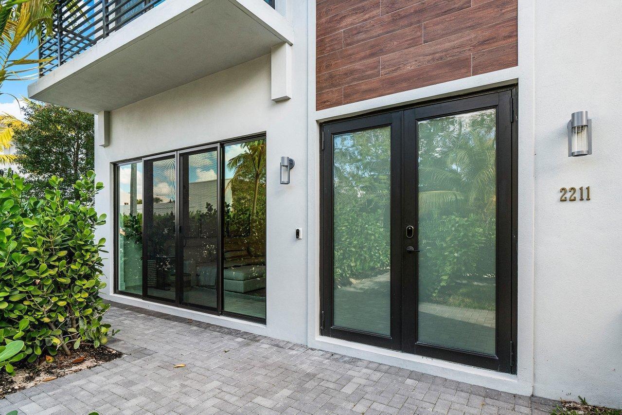 A modern building exterior features a glass sliding door, double entry doors, and wood-look siding — 2211 Florida Boulevard # A, Delray Beach FL 33483, DELRAY BEACH, FL