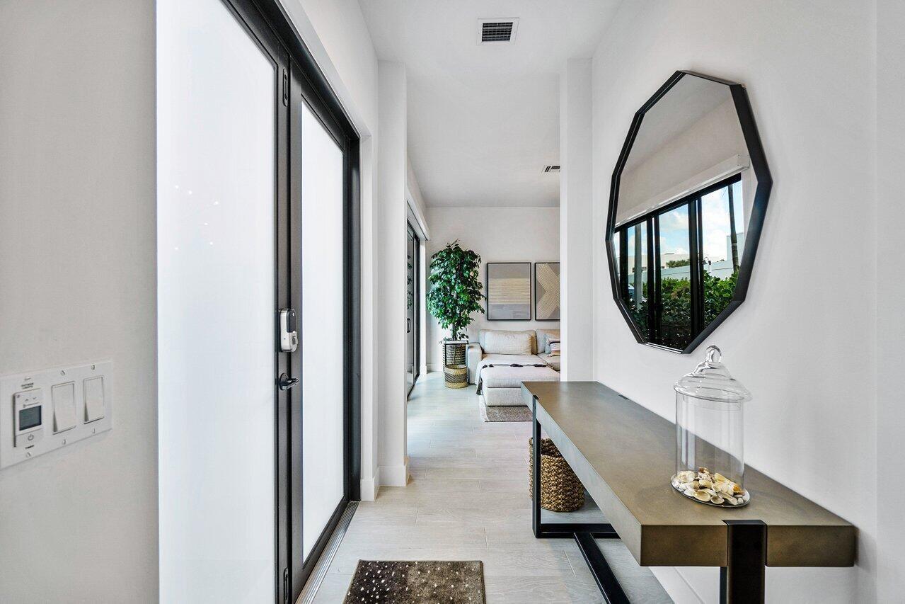 A modern entryway features a console table, an octagonal mirror, and a view into a living area — 2211 Florida Boulevard # A, Delray Beach FL 33483, DELRAY BEACH, FL