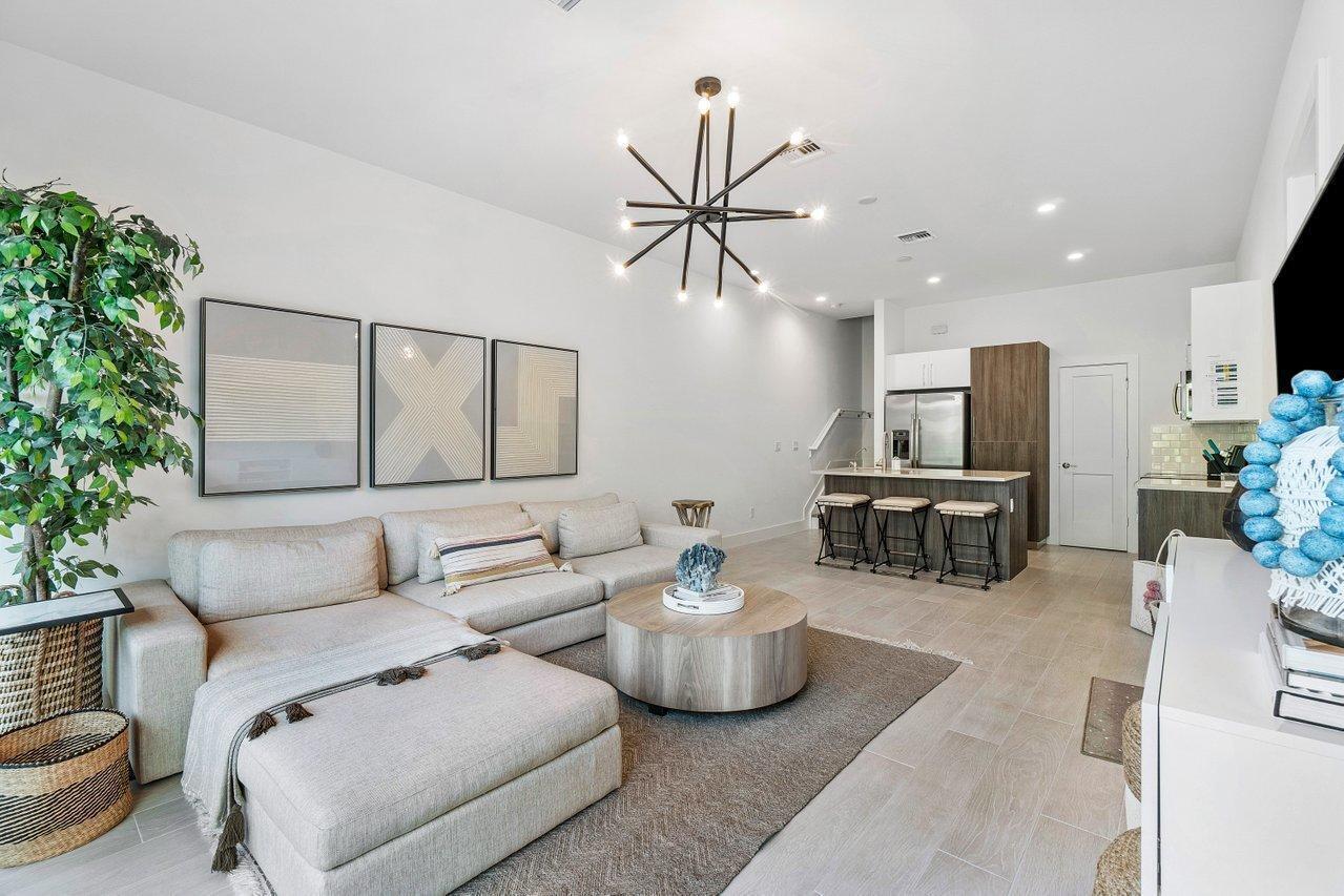 A modern open-concept living room features a sectional sofa, round coffee table, and kitchen island — 2211 Florida Boulevard # A, Delray Beach FL 33483, DELRAY BEACH, FL