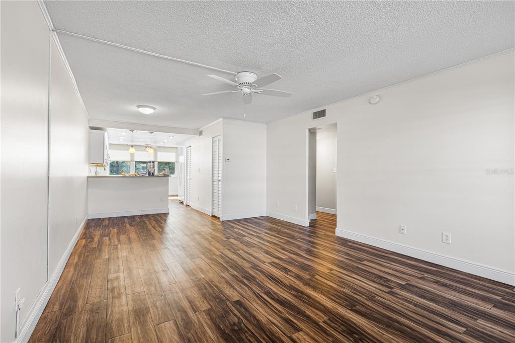 A living room with wood-look flooring, a ceiling fan, and an open kitchen area — 4915 BAY STREET NE UNIT 224, ST PETERSBURG, FL