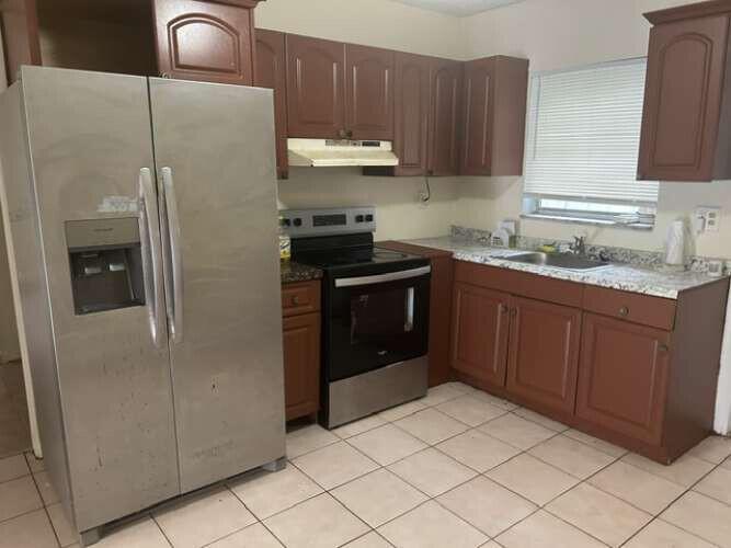 A kitchen featuring brown cabinets, stainless steel appliances, a granite countertop, and tiled flooring — 3370 NW 8th Place, Lauderhill FL 33311, LAUDERHILL, FL