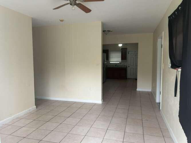 A view of a tiled living area looking toward a kitchen with dark wood cabinets — 3370 NW 8th Place, Lauderhill FL 33311, LAUDERHILL, FL