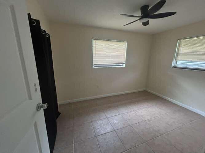 An empty bedroom features beige tile flooring, two windows with blinds, and a ceiling fan — 3370 NW 8th Place, Lauderhill FL 33311, LAUDERHILL, FL