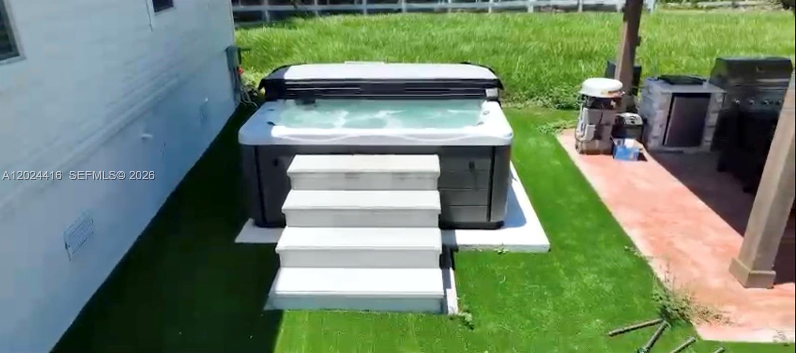 A hot tub with white steps sits on a lawn next to a house — 725 N Willows St, Clewiston FL 33440, CLEWISTON, FL