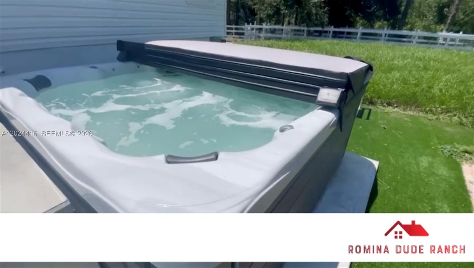 A hot tub with a partially open cover sits on a patio near grass — 725 N Willows St, Clewiston FL 33440, CLEWISTON, FL