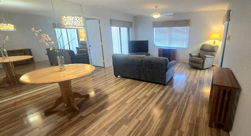 A living and dining area features wood-look flooring, a gray sofa, and a round table — 1001 TARTAN DRIVE UNIT 302, PALM HARBOR, FL
