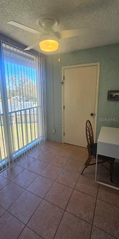 A sunroom with tiled flooring, a ceiling fan, a white door, and vertical window blinds — 1001 TARTAN DRIVE UNIT 302, PALM HARBOR, FL