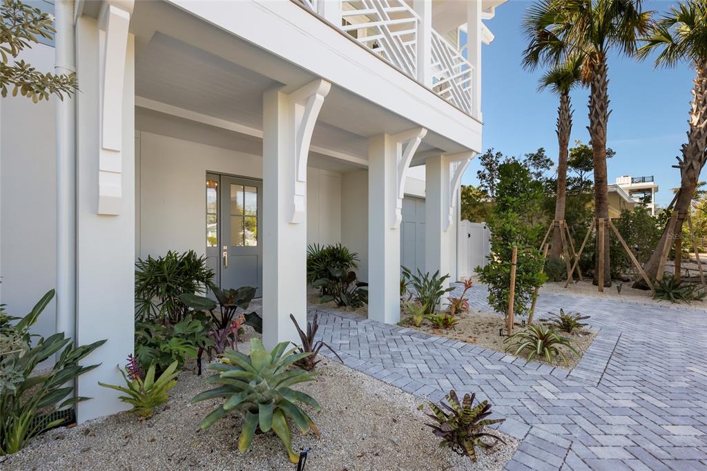 A white house exterior features a covered entryway with decorative brackets and a paved walkway — 215 SYCAMORE AVENUE, ANNA MARIA, FL