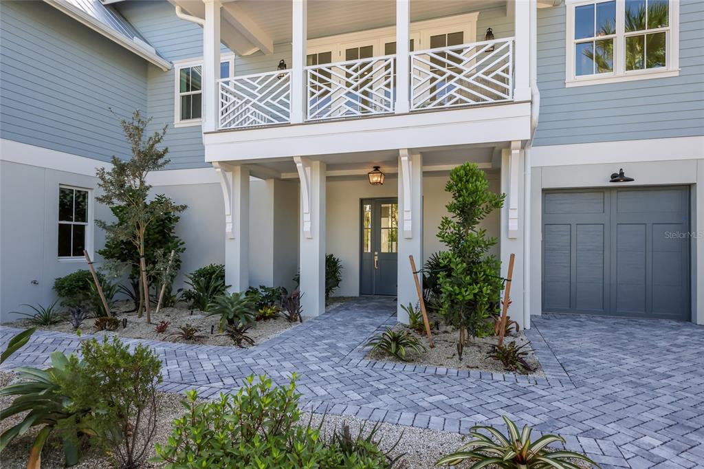 The exterior of a light blue house features a covered entryway, balcony, and paver driveway — 215 SYCAMORE AVENUE, ANNA MARIA, FL
