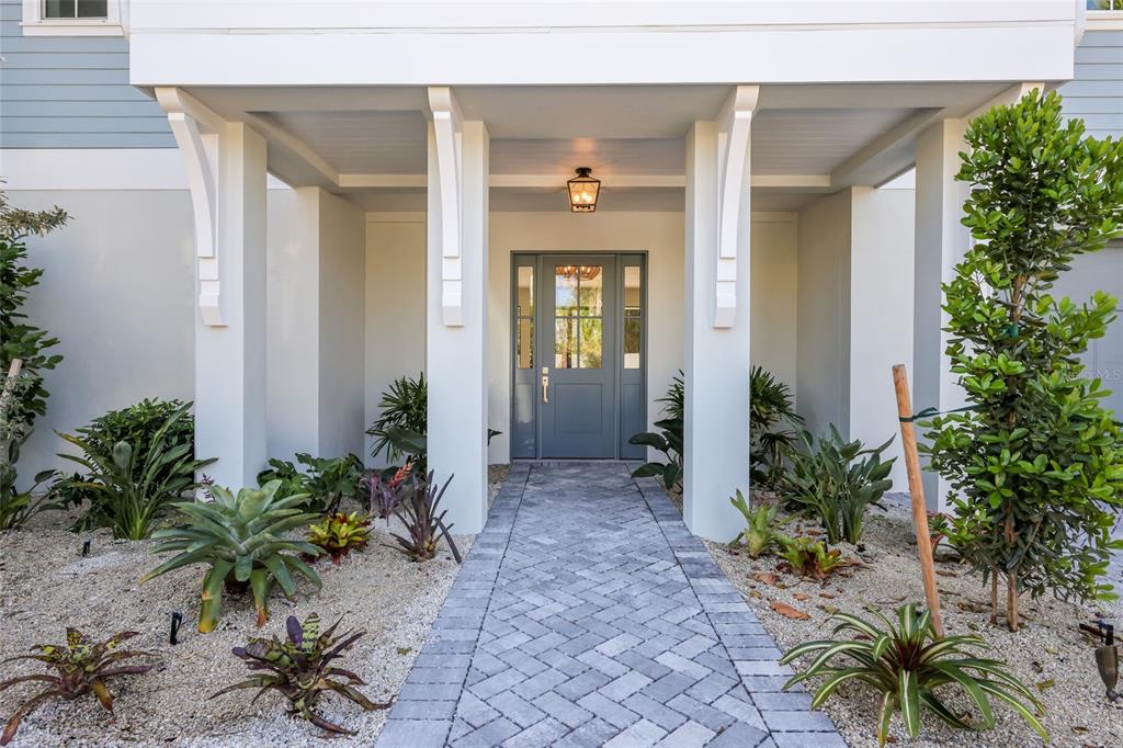 A paved walkway leads to a covered front entrance with white columns and a door — 215 SYCAMORE AVENUE, ANNA MARIA, FL