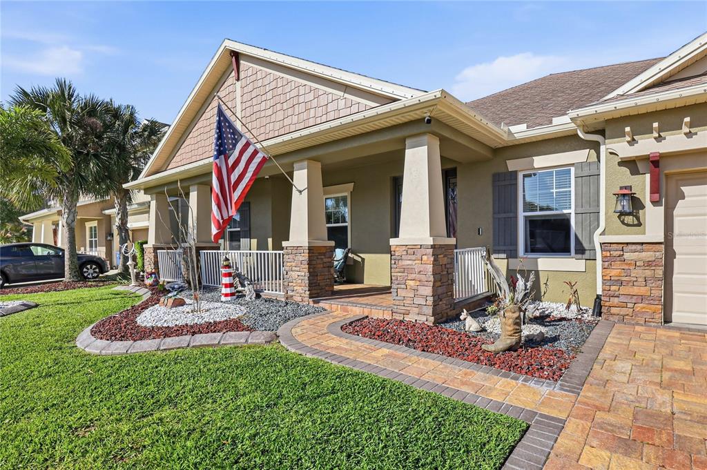 A single-story house with a front porch, stone accents, and a paved driveway at dusk — 1737 VIRGINIA WILLOW DRIVE, WESLEY CHAPEL, FL