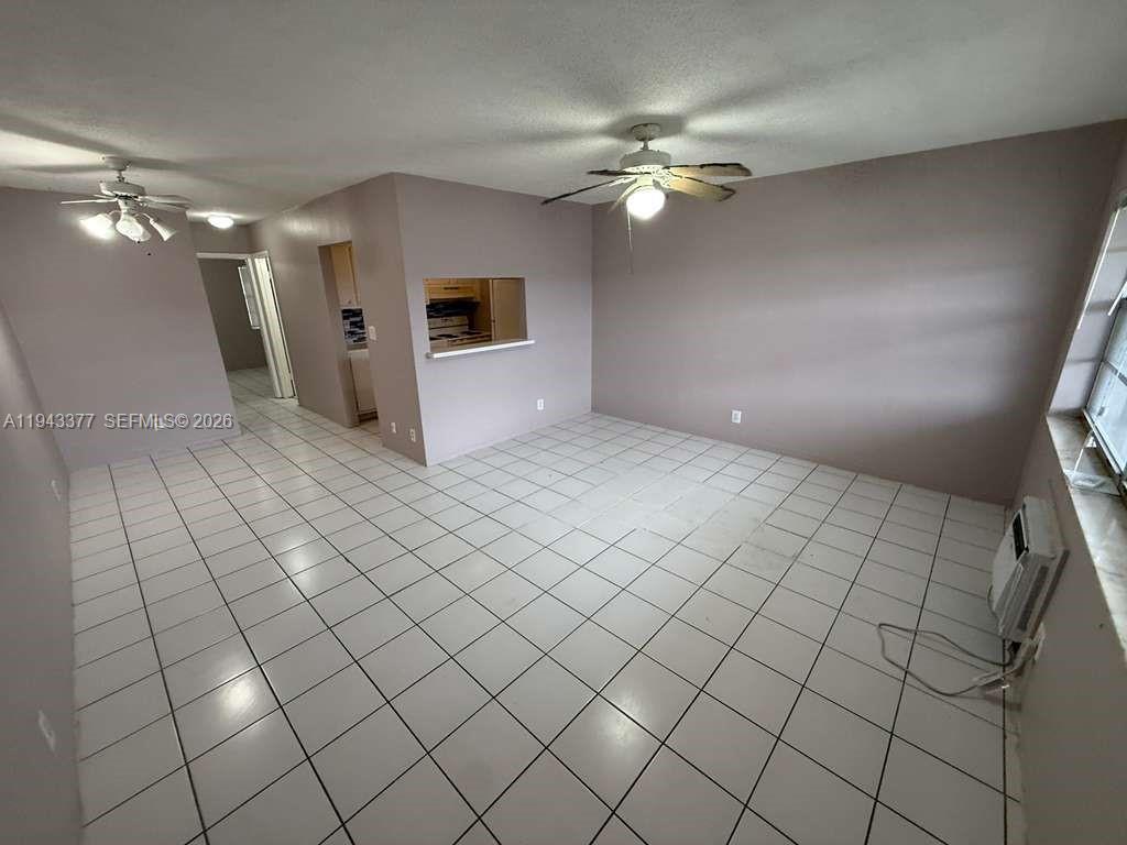 An empty room features white tile flooring, light-colored walls, and two ceiling fans — 2916 Funston St # 53A, Hollywood FL 33020, HOLLYWOOD, FL