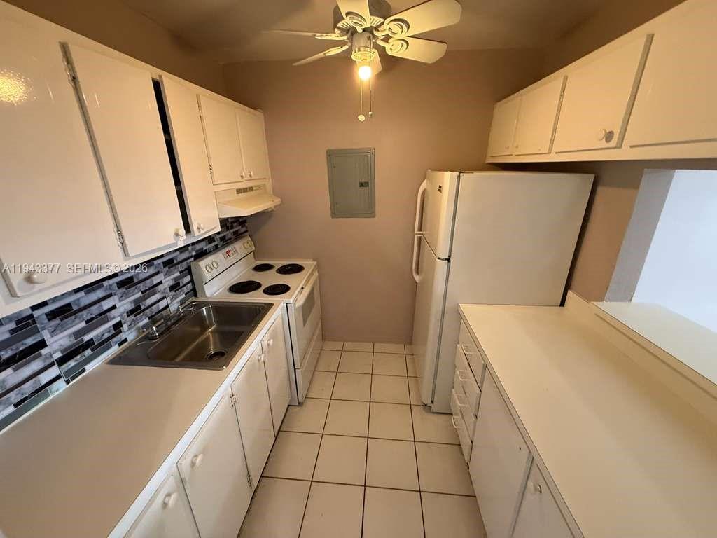 This kitchen features white cabinets, a tiled backsplash, white appliances, and a ceiling fan — 2916 Funston St # 53A, Hollywood FL 33020, HOLLYWOOD, FL
