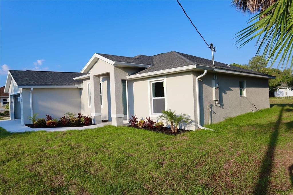A single-story house with a light-colored stucco exterior, a gray shingled roof, and landscaping — 2957 TOMASO ROAD, NORTH PORT, FL