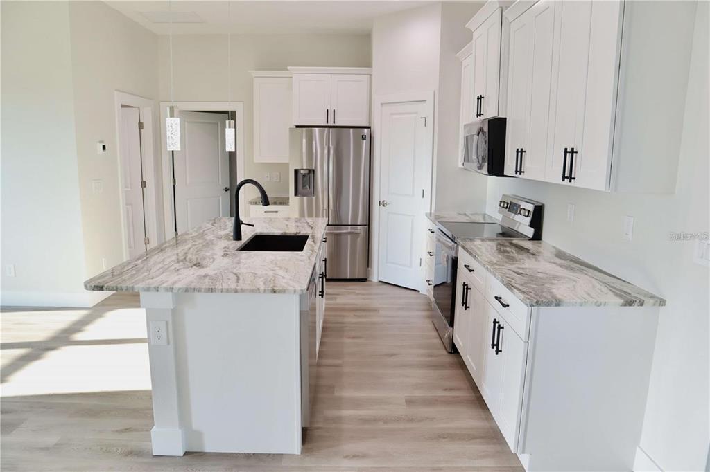 A modern kitchen features white cabinets, stainless steel appliances, and a marble-patterned island countertop — 2957 TOMASO ROAD, NORTH PORT, FL