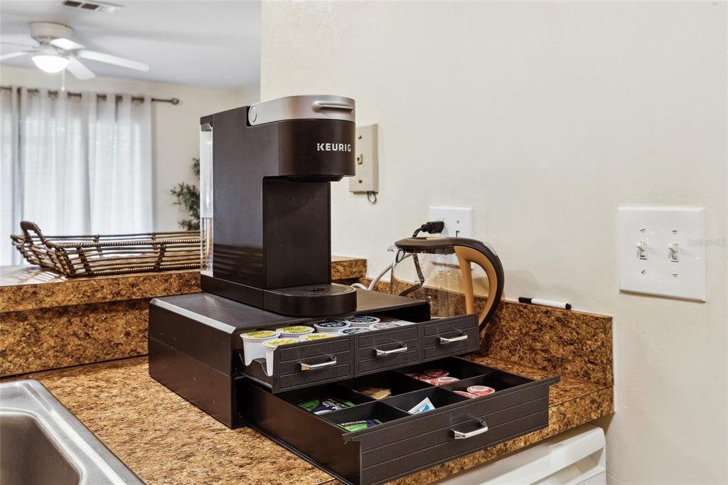 A Keurig coffee maker sits on a storage drawer unit on a brown granite countertop — 2635 SW 35TH PLACE UNIT 1704, GAINESVILLE, FL